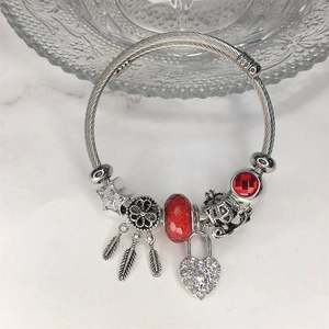 Dettaglio bracciale con ciondoli acchiappasogni, stella e perle di vetro rosso