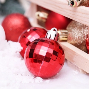 Red faceted Christmas ball and gold glitter ornaments on snow and wooden box display