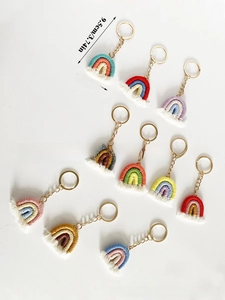 Detail view of colorful macrame rainbow keychains with white fringes and gold rings
