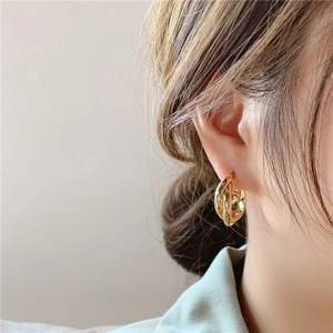 Close-up of gold geometric double layered hoop earrings on a model's ear