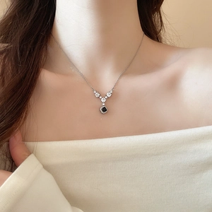 Dettaglio di una collana a Y in argento con gemma quadrata nera indossata sul collo di modella