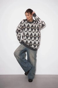 Close-up of diamond pattern knit sweater with horse jacquard and wide-leg denim jeans
