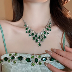 Close-up of elegant silver necklace with emerald water-drop tassels on model