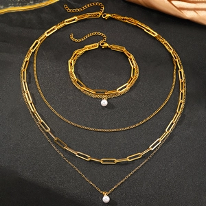 Detailed view of triple-layered gold chain necklace and matching pearl bracelet set