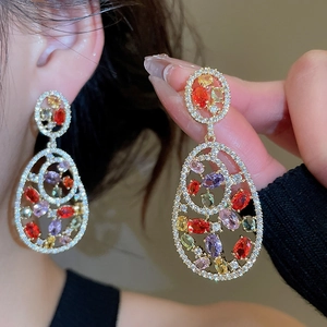 Detail of elegant gold drop earrings with colorful oval crystals on model