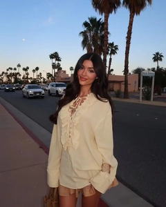 Detail of ruffled chiffon blouse featuring cross-tie V-neckline and tiered flounce sleeves