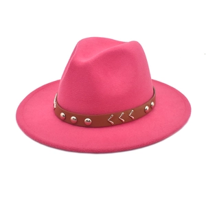 Detail of rose red wool fedora hat featuring a brown leather band and metal V-accents