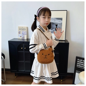 Detail showing soft dark brown teddy bear plush crossbody bag worn by a child