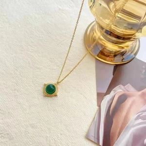Collier vintage doré avec pendentif en agate verte sur fond de tissu beige doux