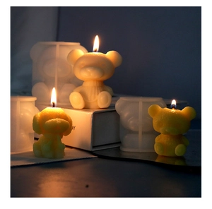Macro shot of 3D teddy bear silicone molds and finished candles with warm lighting