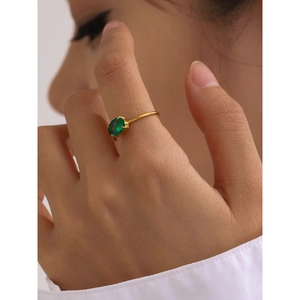 Close-up of gold stainless steel ring with emerald green oval zircon on woman's finger