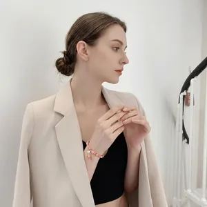 Elegant pink synthetic strawberry crystal bracelet with flower charm on model's wrist