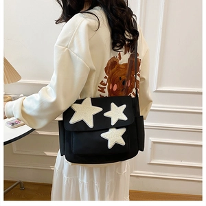 Detail of black canvas crossbody bag featuring three white plush star appliques on back