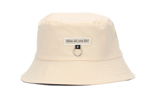 Detail of beige cotton bucket hat featuring embroidered label and metal ring accent