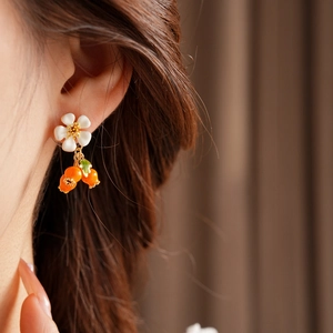 Close-up of model wearing vintage white flower earrings with orange berry pendants