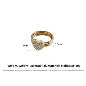 Macro detail of three-tone stackable stainless steel rings with a crystal pavé heart charm
