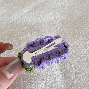Dettaglio del retro di un fermaglio per capelli in maglia viola con clip a becco d'anatra