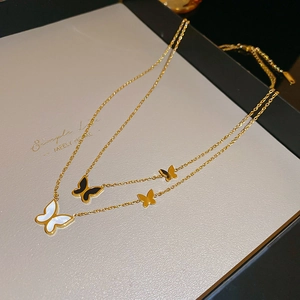 Dettaglio di collana a strati dorata con farfalle in madreperla e ciondoli in smalto nero