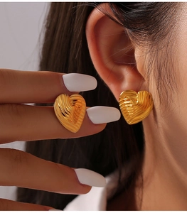 Detailansicht goldener Herzohrringe mit strukturierter Rillenoberfläche am Model