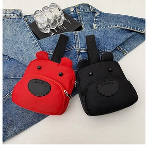Detailed view of red and black cartoon bear tote bags on denim with sleek zipper closure