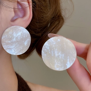 Detailed close-up showing pearlescent white marble texture of large round acrylic earrings