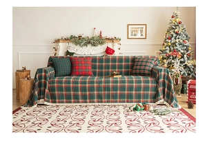 Close-up of red and green plaid Christmas throw blanket with white tassels on a sofa