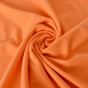 Macro shot of vibrant orange knitted fabric texture showing soft drape and fine fibers