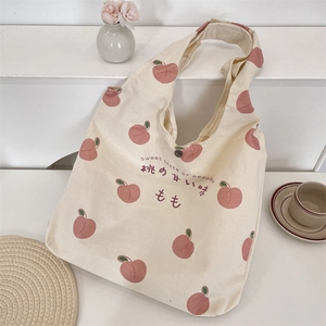 Detail of peach print canvas tote bag featuring metal snap button and soft floral background