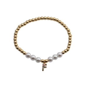 Macro detail of gold beaded bracelet with white pearls and a colorful zircon letter F charm