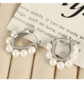 Close-up of elegant small pearl stud earrings with silver U-shaped metal frames