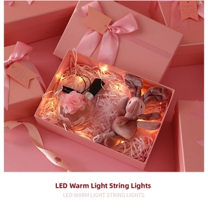 Pink gift box featuring warm LED fairy lights, raffia, and a small plush bunny