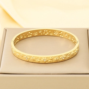 Detail shot of a 18K gold-plated bangle with white zircons on a silk jewelry stand