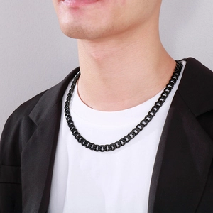 Men wearing a bold black Cuban link chain necklace over a white t-shirt and black blazer