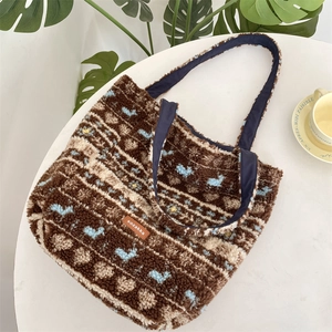 Detail of plush fleece tote bag with brown textures and blue patterns on white table