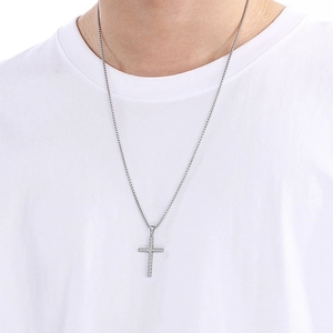 Gros plan d'un collier pendentif croix vintage en argent sur un t-shirt blanc