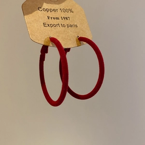 Detailed macro view of red flocked copper hoop earrings with soft velvet surface texture