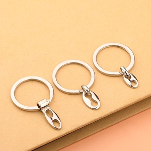 Detailed shot of three silver metal keychains with oval links on a beige paper background