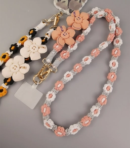 Detail of hand-woven daisy floral phone lanyards with metal clips and SMILE charms