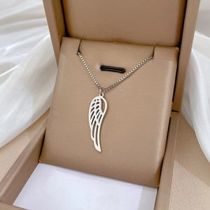 Detailed view of silver hollow wing pendant on box chain inside a beige jewelry gift box