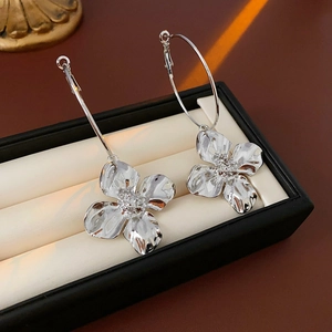 Detail of oversized silver flower drop earrings displayed in a luxury jewelry gift box