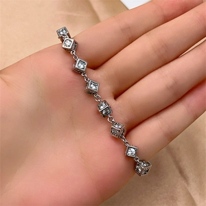 Detail of silver bracelet with cubic links encrusted in sparkling zircons held in hand