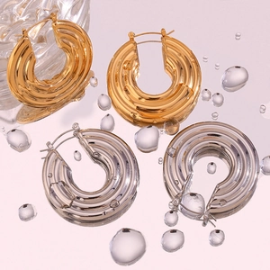 Detail of hollow hoop earrings with triple-layered wave texture in gold and silver finish