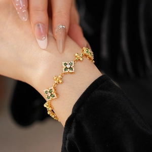 Detalle de una pulsera vintage de oro con piedras verdes y circón blanco en la muñeca