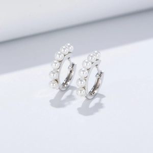Detail view of silver hoop earrings featuring five vertically aligned white pearls