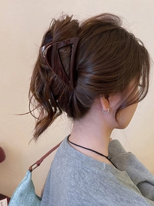 Detail of a large triangular brown acrylic claw clip holding hair in a stylish bun