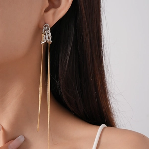 Detail of long mixed-metal chain tassel earrings worn by a model in a close-up shot