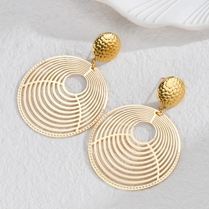Close-up of gold hollow earrings with hammered texture and vintage circular design
