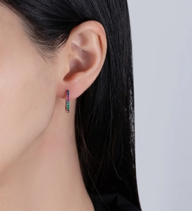 Close-up of model wearing U-shaped silver hoop earrings with multicolored gemstones