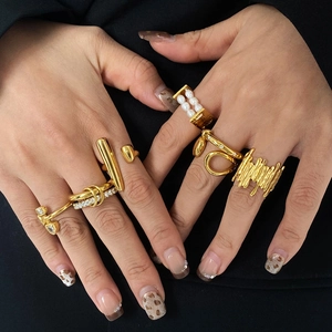 Detail of gold-plated rings with shell and zircon worn against a black suit