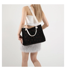 Detail of black corduroy tote bag with red strawberry embroidery and white straps